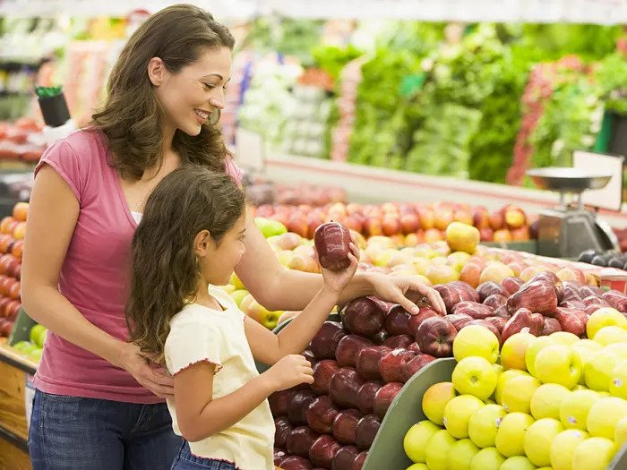 Мать и дочь покупают фрукты в супермаркете