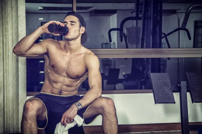 Мускулистый мужчина пьет протеиновый напиток