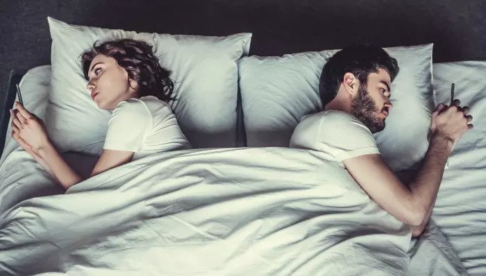 Пары лежат в постели со своими мобильными телефонами