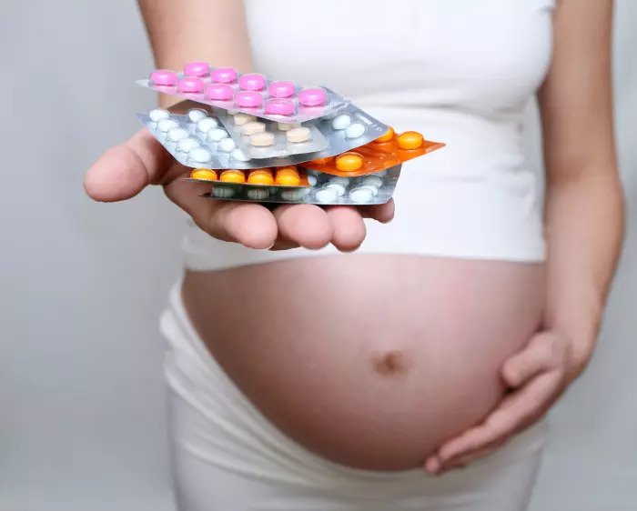Беременная женщина с добавками и таблетками в руках