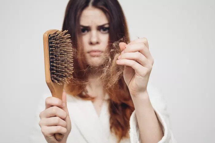 Женщина расчесывает и обнаруживает выпадение волос