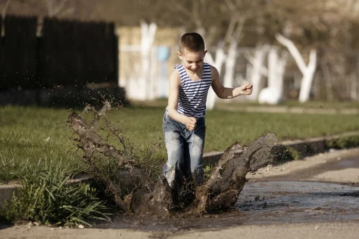 Мальчик прыгает в грязную лужу