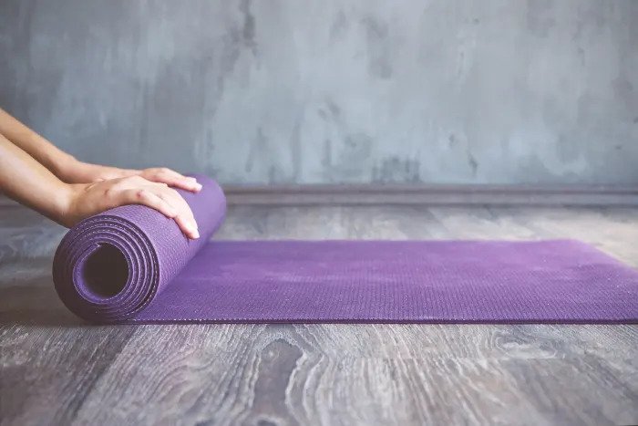 Женщина катает коврик для йоги