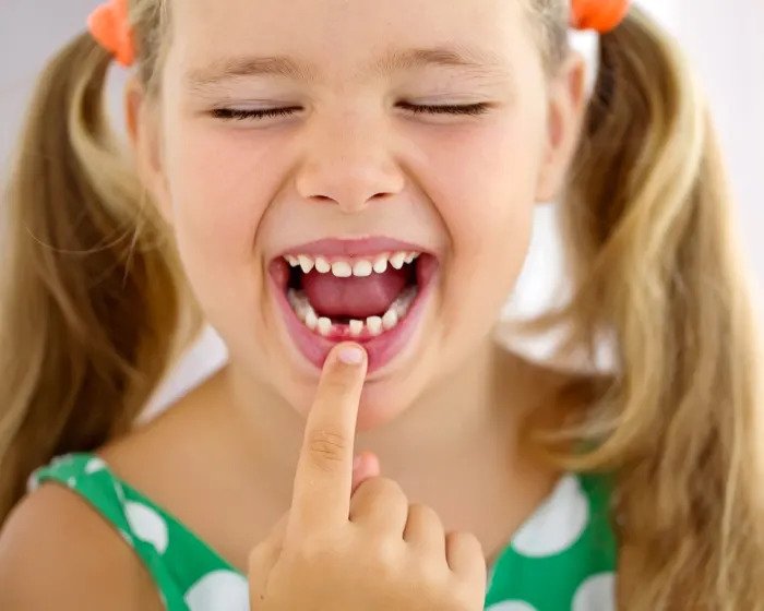 Девушка указывает на выпавшие ей зубы молока
