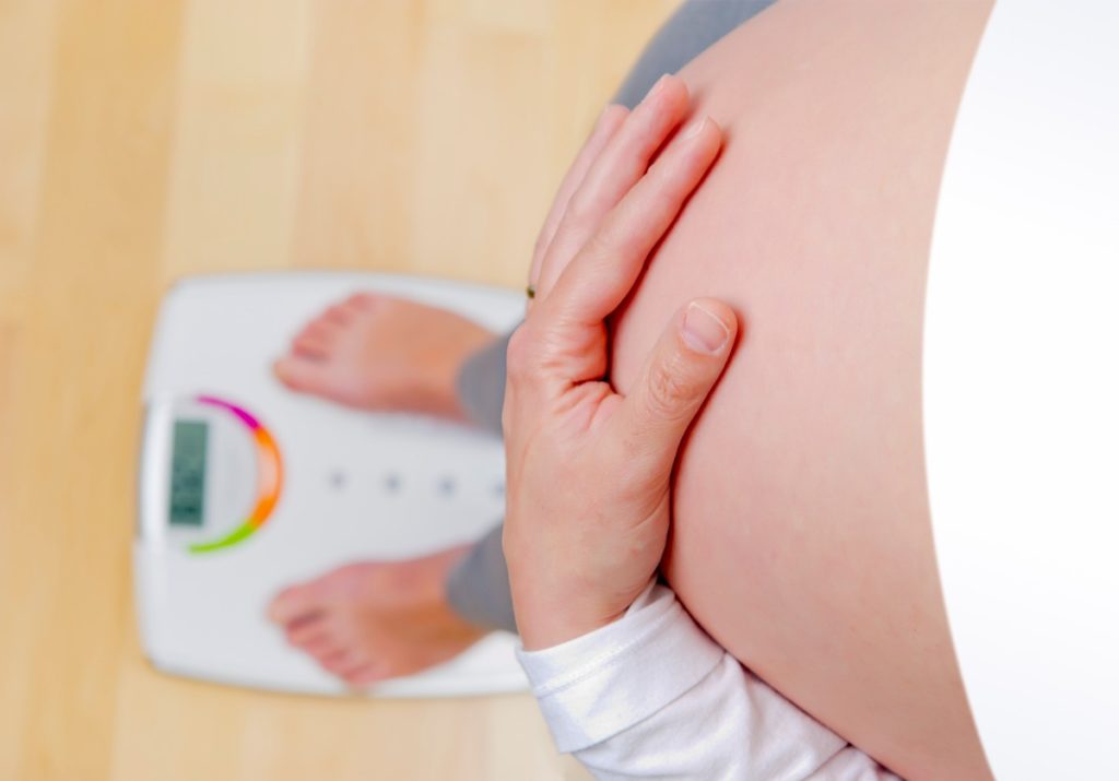Беременная женщина взвешивается на весах