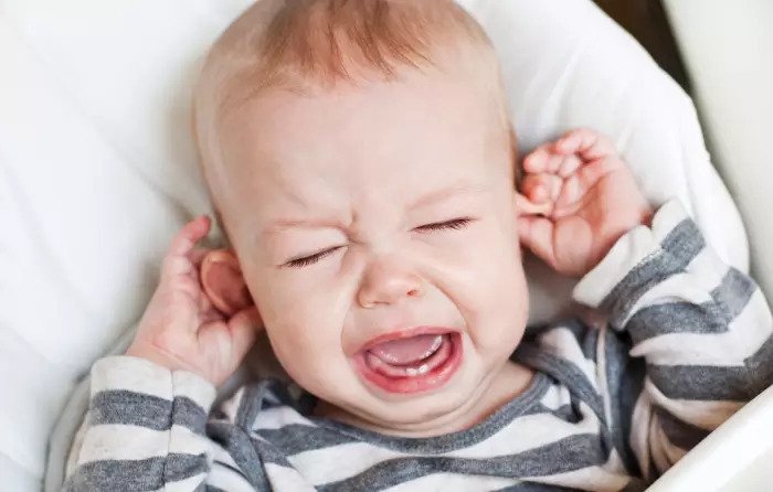 Ребенок плачет и держит уши