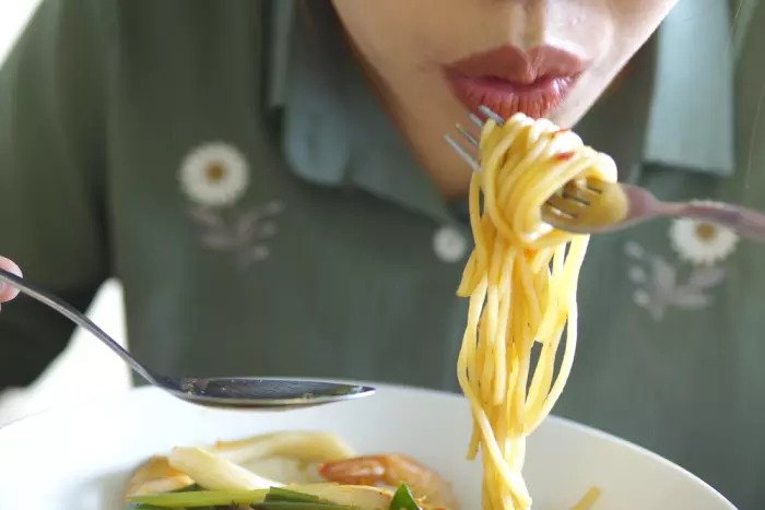 Женщина ест макароны