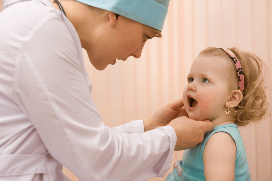 педиатр осматривает слизистые ротовой полости ребенка