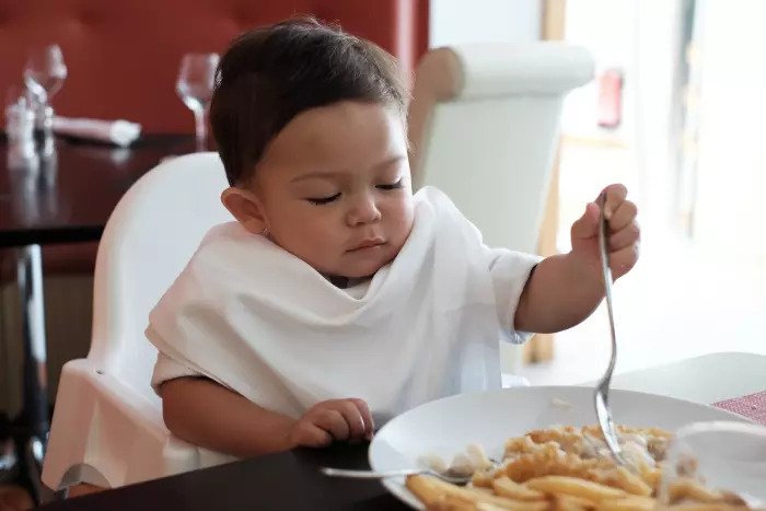 Ребенок ест рыбу с жареным картофелем